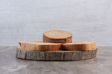 Sticker - Slices of brown bread on a wooden board on marble background