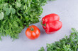 Two piles of various greens with tomato and pepper in between on marble background