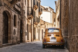 Fototapeta Morze - Old yellow Fiat 500 in the city centre of Syracuse in Sicily, Italy