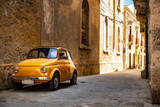 Fototapeta Morze - Old yellow Fiat 500 in the city centre of Syracuse in Sicily, Italy
