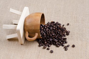 Wall Mural - The coffee beans spill in the coffee wooden cup on the hessian sack  for background , texture , copy text, Love coffee concept