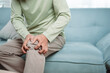 © Kiattisak - Asian Senior man feel knee pain ache. Older mature male hurt at knee while sitting on sofa in living room at home. Bone problam health care and medical insurance concept.