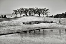 Grayscale Shot Of Fields Partly Covered In Snow By A Pond