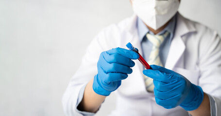 Doctor hand taking a blood sample tube from a rack with machines of analysis in the lab background, Technician holding blood tube test in the research laboratory.