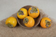 Bunch of ripe delicious persimmons in wooden bowl