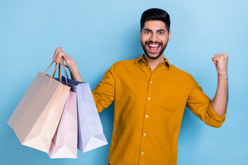 Poster - Photo of cool beard millennial guy hold bags yell wear brown shirt isolated on blue color background