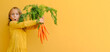 © Maria - Yellow bright. Excited child girl holds big bunch of carrots isolated orange background. Healthy food and vegetarianism. vitamins mineral healthy mock up banner