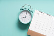 close up of calendar and alarm clock on the green table background, planning for business meeting or travel planning concept