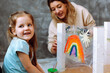 © Татьяна Волкова - Little smiling blond girl painting rainbow on adhesive tape with teacher. Having fun and learning colors in kindergarten