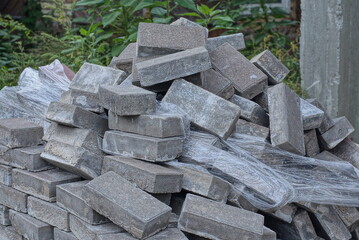 Poster - a pile of gray brick paving slabs and white cellophane packaging on the street