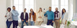 © Studio Romantic - Portrait of friendly and joyful startup colleagues working together in bright office in modern business center. Smart multiracial men and women stand together in row and smile while looking at camera.