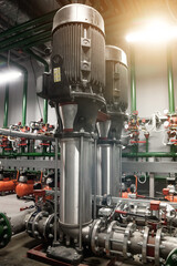 Industrial interior of water pumps, valves, pressure gauges, motors inside engine room. Industry pump in an technical room, urban modern powerful pipelines, automatic control systems. Copy space