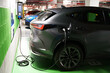 Modern EV electric car charging at public charging station in garage using green electric energy, future of transport concept close-up view