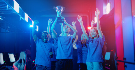 Wall Mural - Banner Happy gamer team winner of video games tournament. Holding big cup trophy of victors cyber gaming esport. Soft focus, neon color