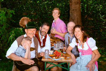 Wall Mural - bavarian family sitting outdoors at beer garden having fun