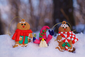 Wall Mural - A fabulous dwarf made of plasticine with a glass of champagne in his hand against the background of snow. Next to the toy gingerbread man. Beautiful fabulous Christmas figurines.