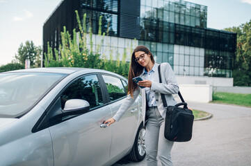 business woman getting into the car and using smartphone