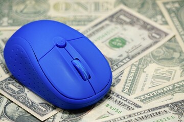 Closeup of a blue computer mouse placed on top of dollar banknotes