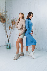 Wall Mural - Two pretty women in stylish clothes and white leather boots. Autumn female image.