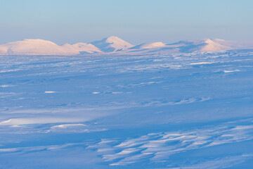 Wall Mural - Winter arctic landscape. View of the snow-covered tundra and snow-capped mountains. Cold frosty winter weather. The harsh nature of polar Siberia and Chukotka. Travel to the extreme North of Russia.