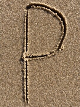On the beach in the sand is carved the letter P