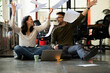 © JustLife - Colleagues celebrating in the office. Businesswoman and businessman sitting on the floor. Colleagues working on the project