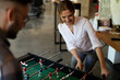 © JustLife - Colleagues having fun at work. Businessman and businesswoman playing table soccer.
