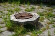 an old abandoned well with a rusty lid, on a terrace overgrown with grass