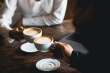 Fototapeta  - Close-up of a man and woman clinking a white coffee cup in a coffee shop. while talking at work