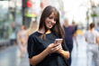 © Adam Radosavljevic - Beautiful smiling woman in black shirt texting on smartphone on street in city center