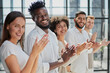 © Katsiaryna - Group of businesspeople sitting in a line and applauding.