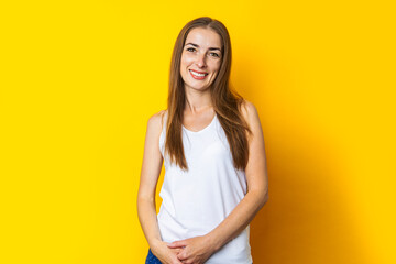 Wall Mural - Beautiful smiling young woman with long hair on a yellow background