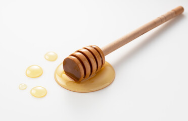 Wall Mural - Wooden honey dipper with honey on white background.