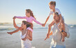 © Alex S/peopleimages.com - Family, kids and holiday at the beach with parents with children on mom and dad shoulder. Vacation, having fun and taking a walk by the ocean. Summer, seaside and exercise in the morning by the sea