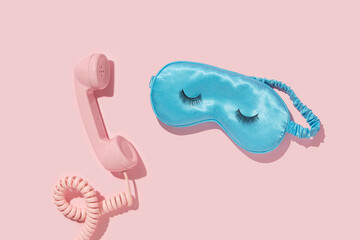 Wall Mural - Creative layout with pink retro phone handset and sleep mask with false eyelashes on pastel pink background. 80s or 90s retro fashion aesthetic telephone concept. Romantic handset cosmetic  idea.