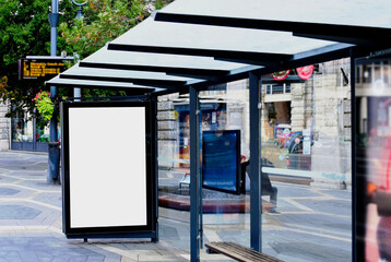 Wall Mural - bus shelter image composite. bus stop. blank white lightbox and glass structure. poster ad commercial poster space. mockup base. city street setting. urban background. aluminum frame. green trees.