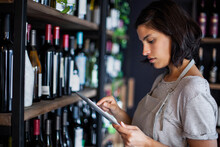 Wine Store Female Worker Taking Inventory On Digital Tablet