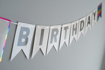 Wall Mural - Birthday ribbon in capital letters on a solid grey blue background