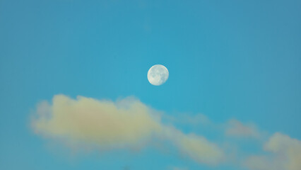 morning moon on a blue sky with clouds background