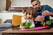 © Svitlana - Father teach son fix skateboard on sofa at home