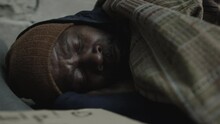 Close Up Shot Of African American Homeless Man In Knitted Hat Sleeping In Rags On Ground