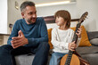 © Svitlana - Dad and son with acoustic guitar on sofa at home