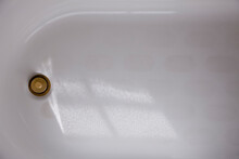 A White Enamel Bathtub With A Brass Plug Or Drain Cover, Overhead View.