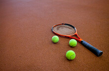 A Hard Tennis Court And A Tennis Raquet,with Three Balls.