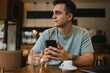 © Dusan - A young guy using his computer in cafe and talking on the phone while drinking water and coffee