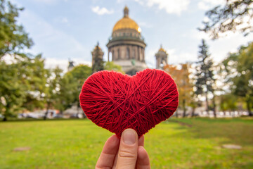 Red heart in hand against the background of the St. Isaac's Cathedral, St. Petersburg, Russia