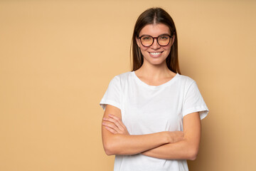 Wall Mural - Woman in white mockup t-shirt and glasses on brown copy space background with crossed hands