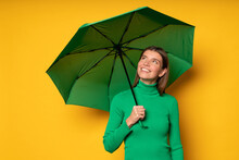 Romantic Woman Hiding Under Umbrella On Rainy Day Looking Up On Cloudy Sky On Yellow Background