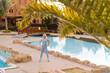 © Angelov - Good morning with yoga meditating on sunrise background. Active woman practicing at villa poolside to keep fit and health. Woman fitness training, sport activity on summer family holiday.