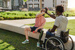 Multiracial people with physical disabilities greeting each other outdoor - Focus on right man sitting on wheelchair